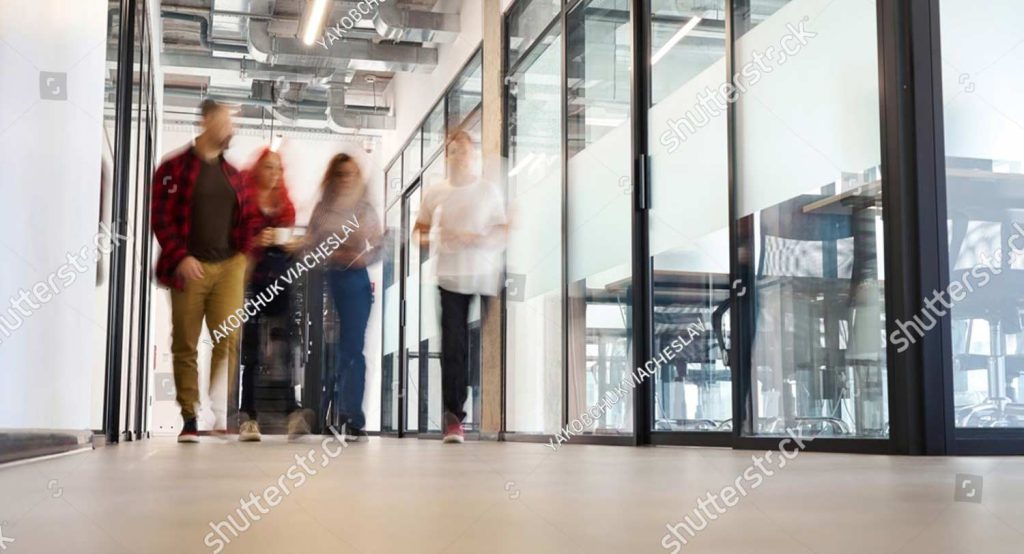 stock photo blurred view people walking along bright office hall with big panoramic windows 2417840307 stock photo blurred view people walking along bright office hall with big panoramic windows 2417840307